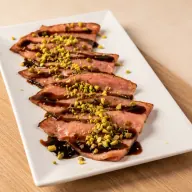 Grilled Pistachio Mortadella — Pistachio mortadella seared on the griddle, pistachio pesto, crushed pistachios and balsamic glaze